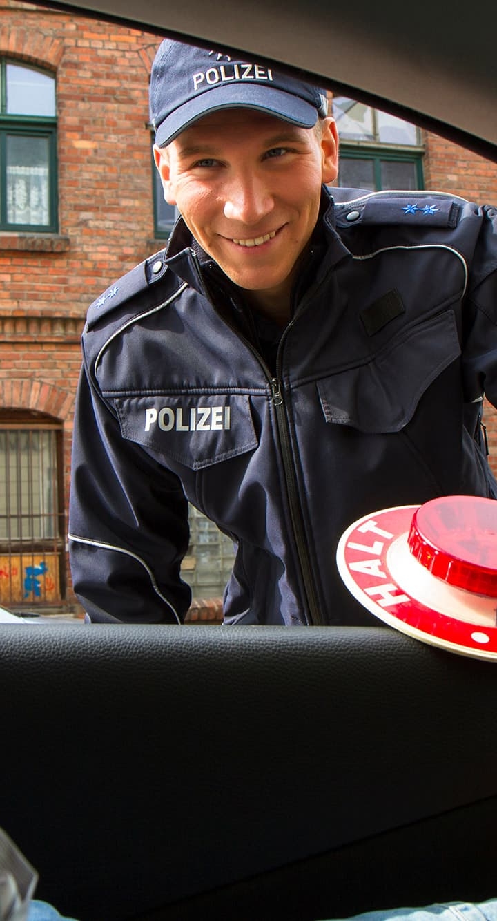 Ppolizist in blauer Uniform beugt sich freundlich lächelnd